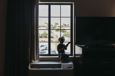 Young toddler boy sitting in window of hotel room in palm springs