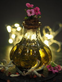 Close-up of illuminated flower in glass jar on table