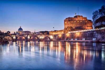 Arch bridge over river by buildings against sky in city