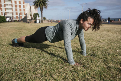 Woman doing push ups on the grass.