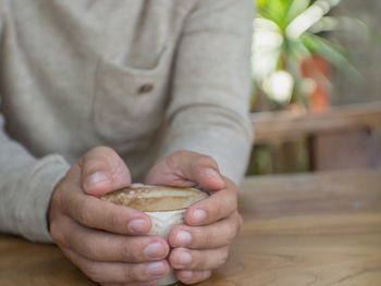 Close-up of hand holding baby sitting on table