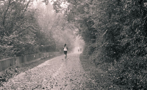 Rear view of two people walking on footpath