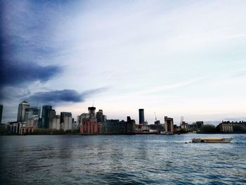 River by buildings in city against sky