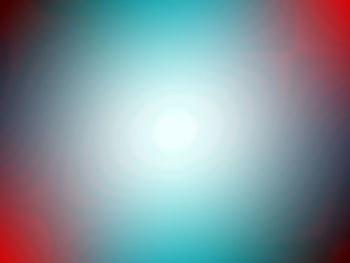 Defocused image of illuminated lights against blue sky