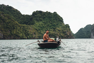 Man on boat in sea against sky