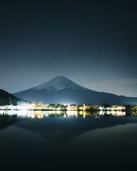 Scenic view of lake by mountains against sky at night