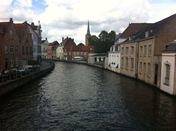 Canal amidst buildings in town against sky