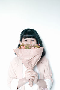 Portrait of woman holding bouquet against white background