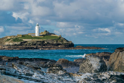 Lighthouse by sea against sky