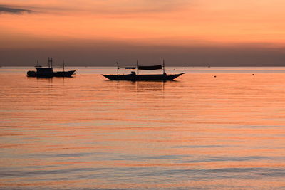 Silhouette sailboat in sea against sky during sunset