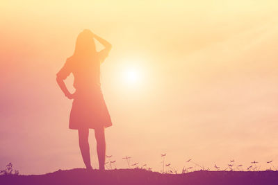 Silhouette woman standing on land against sky during sunset