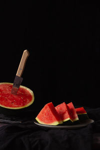 Close-up of fruits served on table against black background