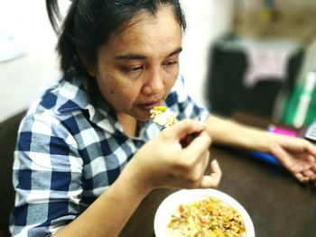 High angle view of mature woman eating food while sitting at table