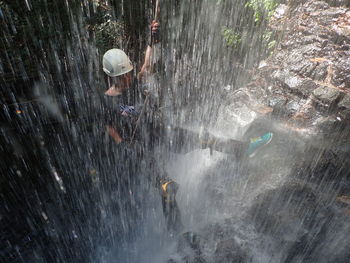 Man doing rock climbing at waterfall