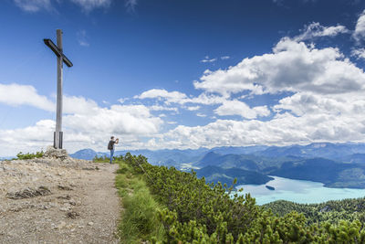 Man photographing while standing on mountain against sky