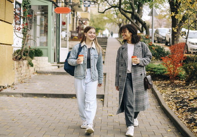 Portrait of young woman walking on footpath