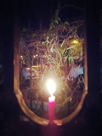 Close-up of lit candle in window