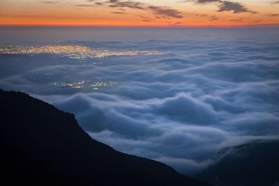 Scenic view of mountains against cloudy sky at sunset