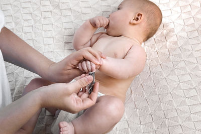 Mother cuts her baby's nails with scissors while he sleeps. nursing a child. clipping. how to
