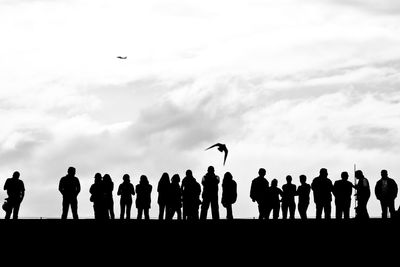 Low angle view of people against cloudy sky