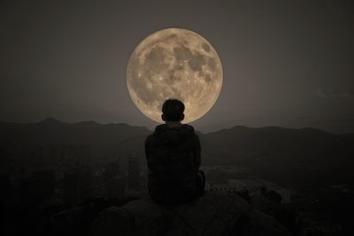 Rear view of silhouette man standing against moon at night