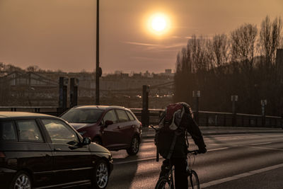 Man with bicycle on road in city during sunset