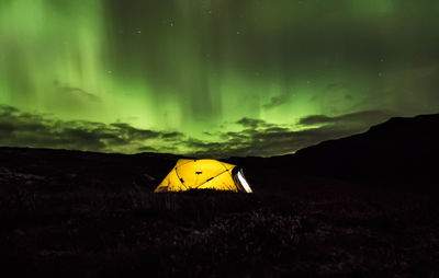 Illuminated tent on field against sky