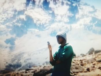 Full length of man using mobile phone against sky