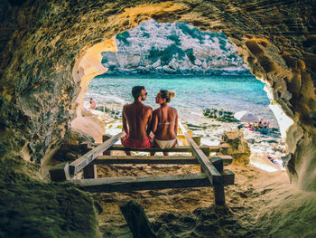 People sitting on rock by sea