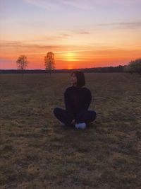 Man sitting on field during sunset