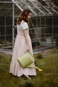 Pretty woman at her 30s in the garden with watering can walking on the grass. beautiful dreamlike