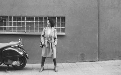 Full length of woman standing against wall in city