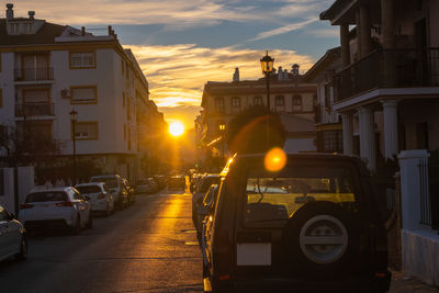 Cars on street against sky during sunset