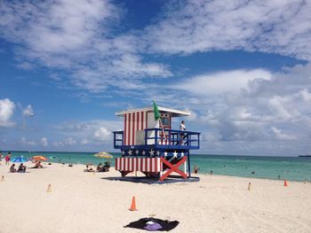 Low angle view of man standing on lifeguard hut at beach against sky