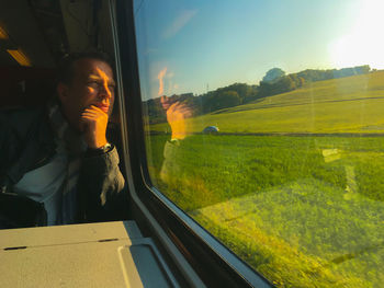 Mature man looking through window while traveling in train