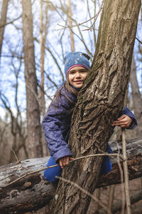 Portrait of boy on tree trunk during winter