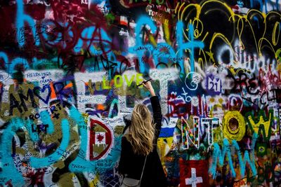 Rear view of woman painting on john lennon wall