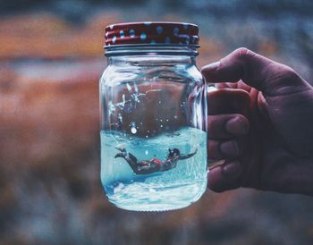 Cropped hand with woman swimming in jar