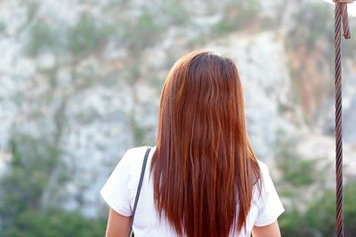 Rear view of woman with arms raised standing outdoors