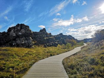 Footpath leading towards mountains against sky