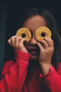 Portrait of girl holding cookies in front of eyes