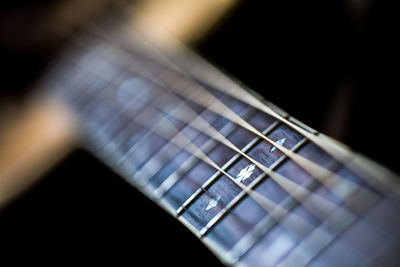 Close-up of guitar fretboard over black background