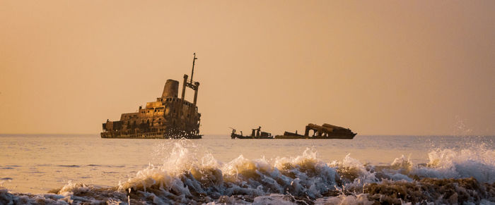 Scenic view of sea against clear sky during sunset with shipwreck