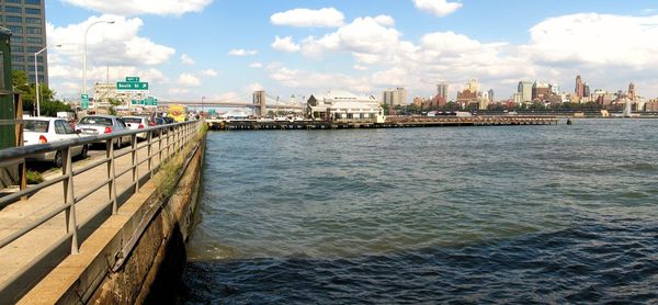 City at waterfront against cloudy sky