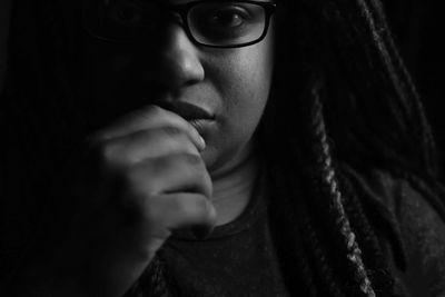 Close-up portrait of young woman against black background