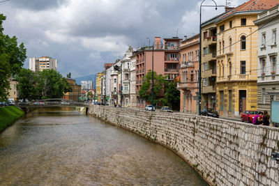 Canal amidst buildings against sky in city