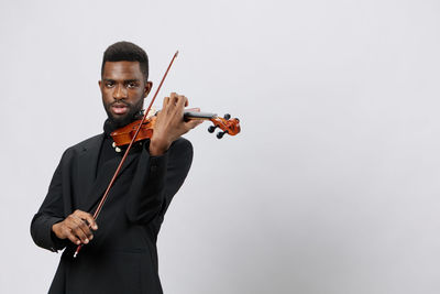 Young woman playing violin against white background