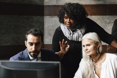 Confident financial experts discussing over computer during meeting at office