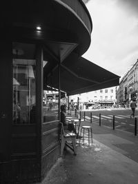 Empty chairs and tables in restaurant against buildings in city