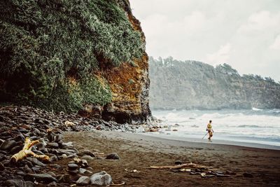 Person walking on beach against cloudy sky